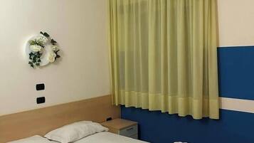 A hotel room with a bed, a nightstand, a wall-mounted telephone, and a decorative wall piece.