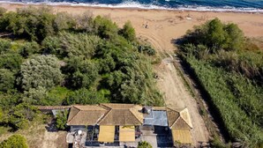 An aerial view of a coastal property with a house, surrounded by dense vegetation and a beach. - Beach House Steps Away From the sea (Pylos-Nestoras)