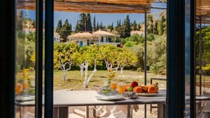 A table with breakfast items and a view of a vineyard. - Beach House Steps Away From the sea (Pylos-Nestoras)