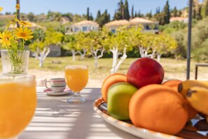 A table with a fruit bowl, two glasses of orange juice, and a cup. - Beach House Steps Away From the sea (Pylos-Nestoras)