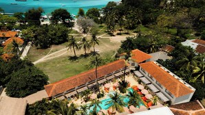 A resort with a swimming pool, palm trees, and a view of the ocean with boats. - Divino Gili Air (Gili Air)
