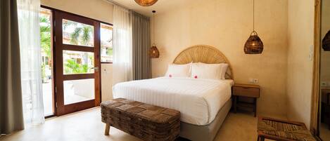 A bedroom with a large bed, a wooden bench, two bedside tables, and a large mirror.