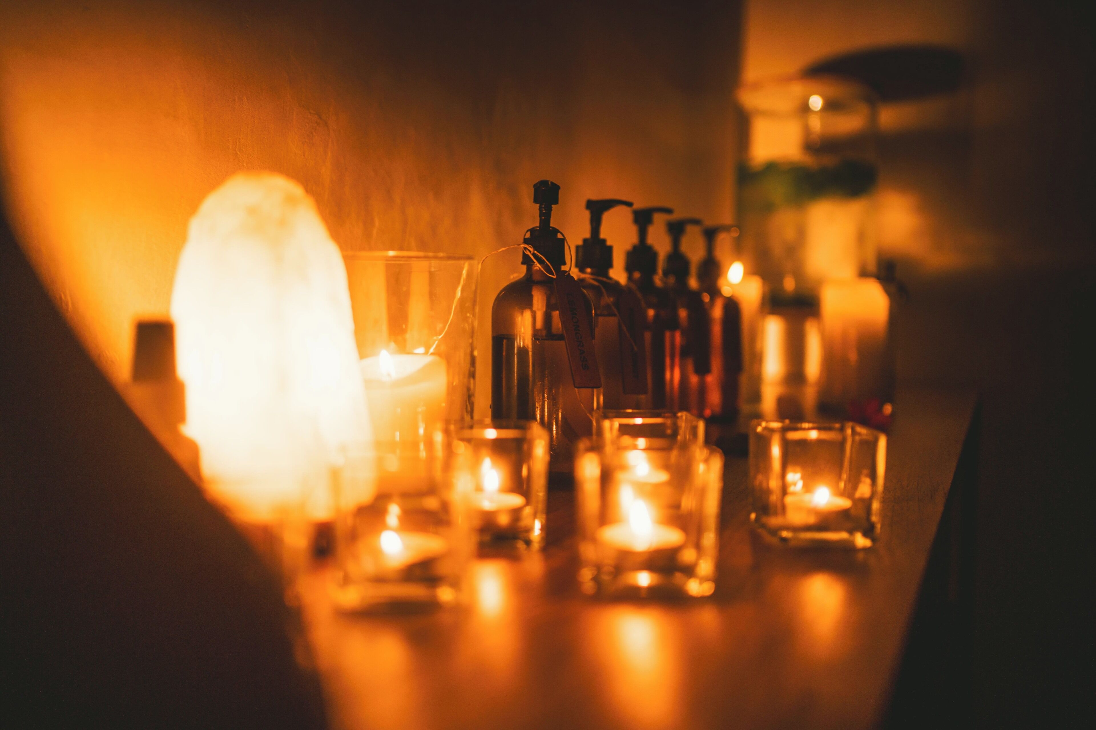 A dimly lit room with candles, bottles, and a glass.