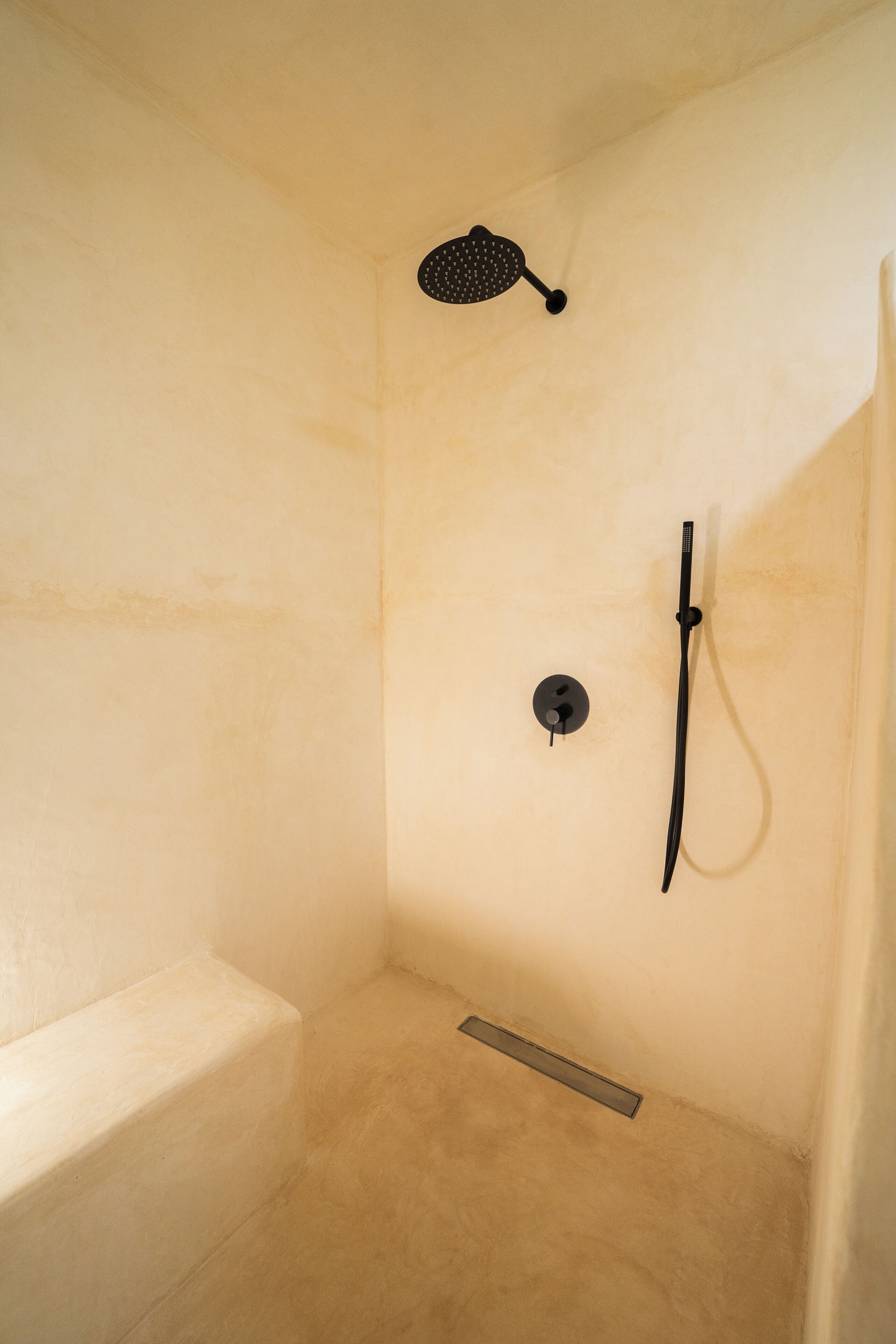 A shower with a handheld showerhead and a wall-mounted faucet.