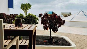 A patio area with a table, chairs, and potted plants. - Canaryislandshost l Amapola (Las Palmas)