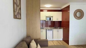 A compact living space with a kitchenette, a sofa, and a decorative mirror. - Canaryislandshost l Amapola (Las Palmas)