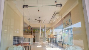 A modern interior with a glass door, ceiling fan, and seating area with a sofa and chairs. -  Indie Stays Studio Kharadi (Pune)