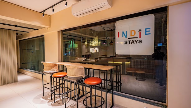 A modern interior with a bar area featuring stools and a glass partition. -  Indie Stays Studio Kharadi (Pune)