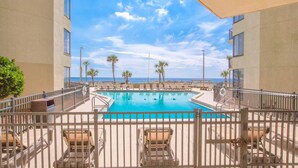 A pool area with lounge chairs and palm trees, overlooking the ocean. - Sunbird Beach Resort #902 - Oceanfront Escape | Gulf Front (Panama City Beach)