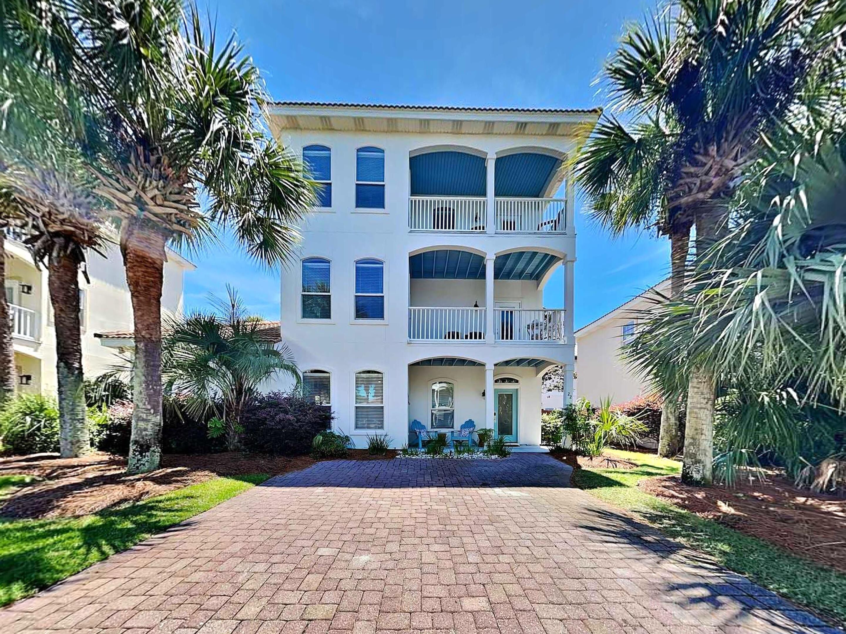 A multi-story building with a central entrance, surrounded by palm trees and a paved driveway.