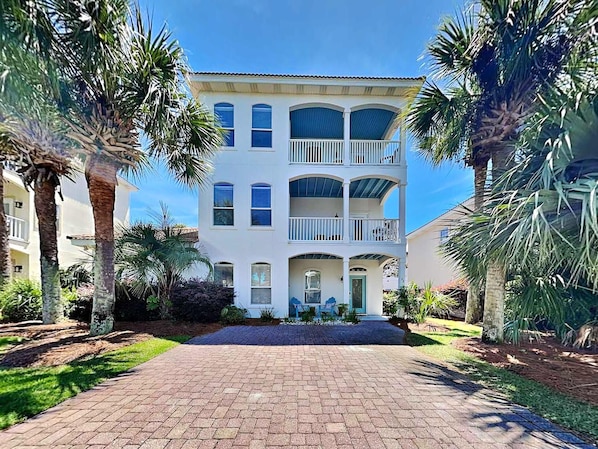A multi-story building with a central entrance, surrounded by palm trees and a paved driveway. - 30A Dreamin | Four Bikes Included + Easy Beach Access (30A)