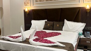 Quarto de hotel com cama, ventilador de teto, luminárias fixadas na parede e chão quadriculado.