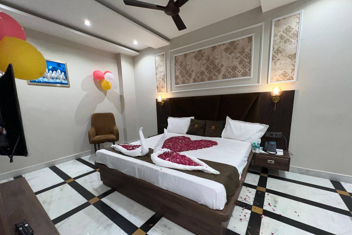 Une chambre d’hôtel avec un grand lit, une chaise, un bureau et un ventilateur de plafond.