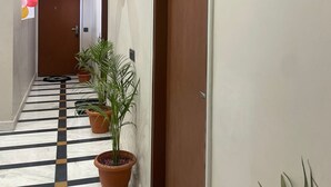 Um corredor de hotel com piso xadrez, plantas em vasos e balões.