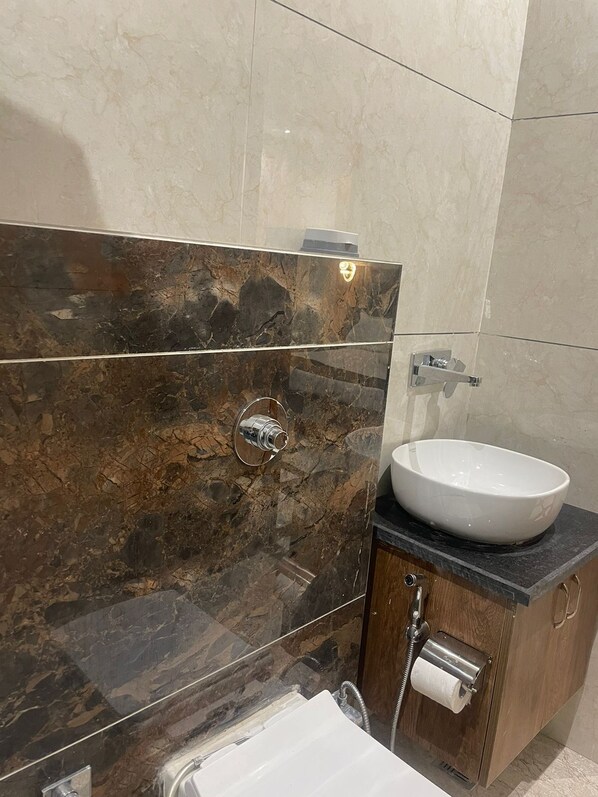 Une salle de bain avec un meuble-lavabo en marbre, un lavabo blanc et des toilettes.