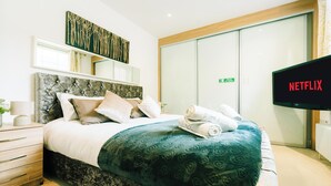 Camera d'albergo con un letto, una TV che mostra 'NETFLIX', un armadio con ante scorrevoli e un'opera d'arte appesa al muro.