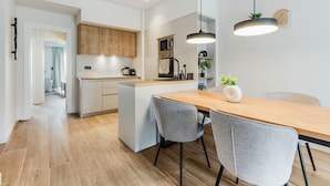Una cucina moderna con mobili in legno, un'isola centrale e un'area pranzo con due sedie grigie.