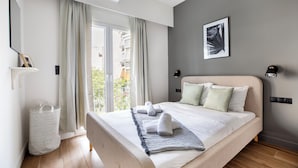 Una camera da letto moderna con un letto grande, vista sull'esterno, un'opera d'arte incorniciata a parete e una lampada da comodino.
