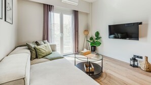 Una camera d'albergo moderna con un letto grande, una TV a schermo piatto, un tavolino in vetro e una pianta in vaso.