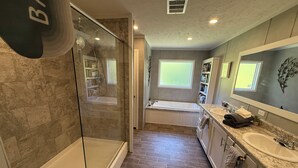 A modern bathroom with a glass-enclosed shower, a bathtub, and a vanity with a sink.