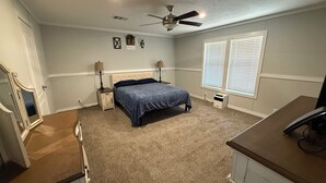 A bedroom with a bed, bedside tables, a ceiling fan, and a window with blinds.