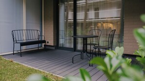 A modern outdoor seating area with a bench and two chairs, a glass door, and a brick wall. - Apartamenty Sun & Snow Nadmorska Florina (Leba)