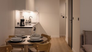 A compact kitchen with modern appliances, a dining table set for four, and a cozy seating area with a sofa and armchair. - Apartamenty Sun & Snow Nadmorska Florina (Leba)