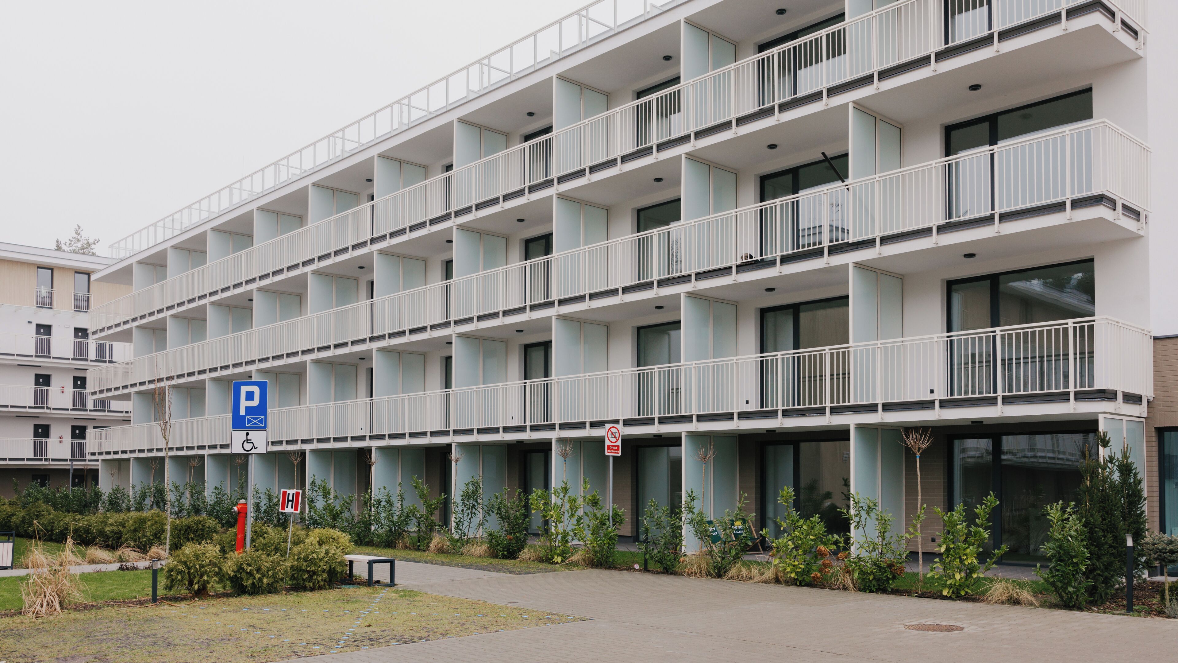 Een meerlaags hotel met een parkeersbord, een rookverbodsbord en een bord met informatie over toegankelijkheid voor mensen met een handicap.