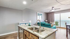 A modern kitchen with a marble countertop, wooden cabinets, and a built-in sink.