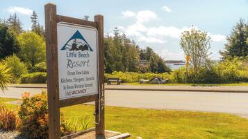 A sign for Little Beach Resort with amenities like Ocean View Cabins, Kitchens, Sleepers, and Jacuzzi, and a note that it is not currently vacant.
