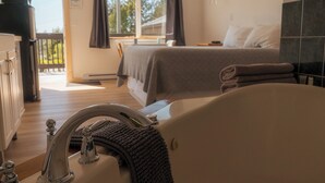 A hotel room with a bed, a bathtub, and a view of the outdoors. - Little Beach Resort (Ucluelet)