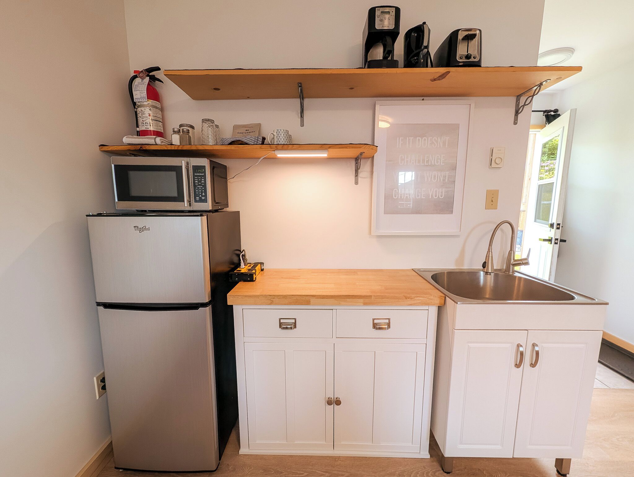 Eine kleine Küche mit Kühlschrank, Mikrowelle und einer Holz Arbeitsplatte.