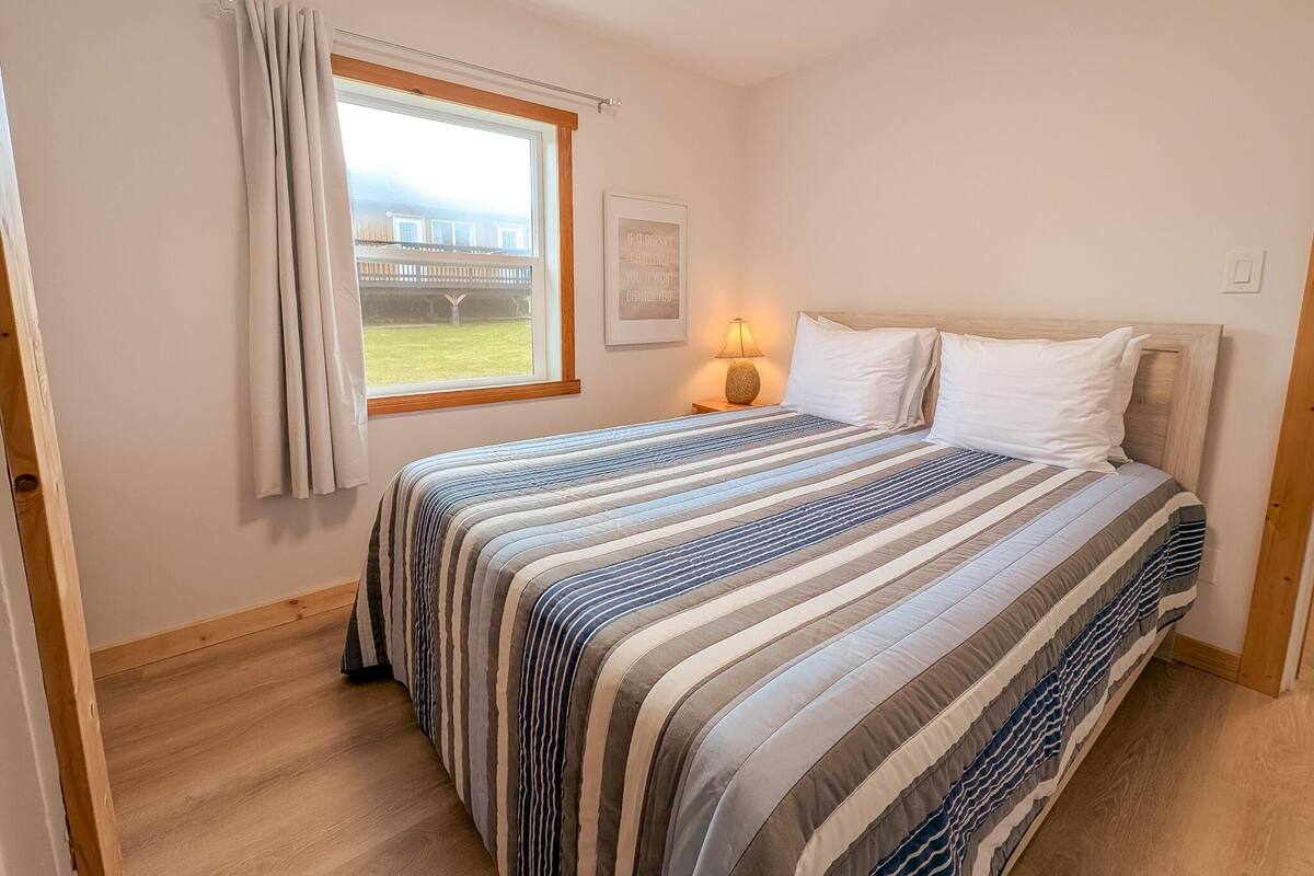 Une chambre à coucher avec un lit, une fenêtre avec des rideaux, une lampe de chevet et une vue sur un pont.