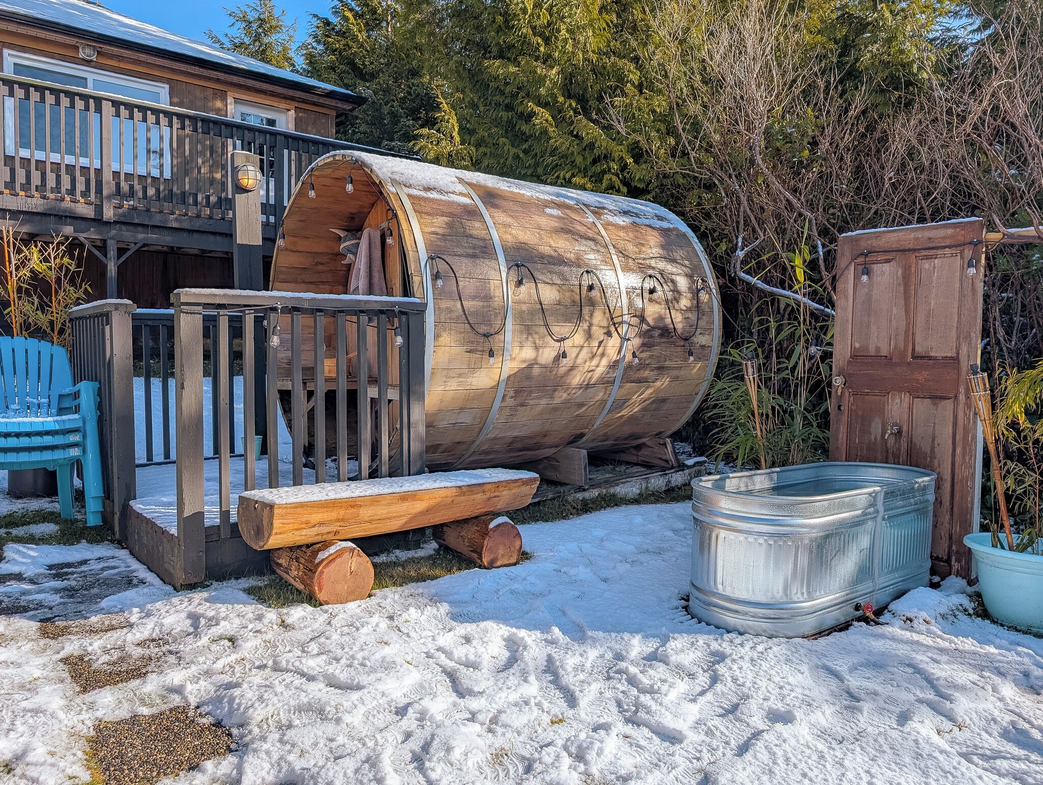 Une cabane rustique avec une structure en forme de tonneau en bois, une terrasse en bois et un bain à remous en métal.