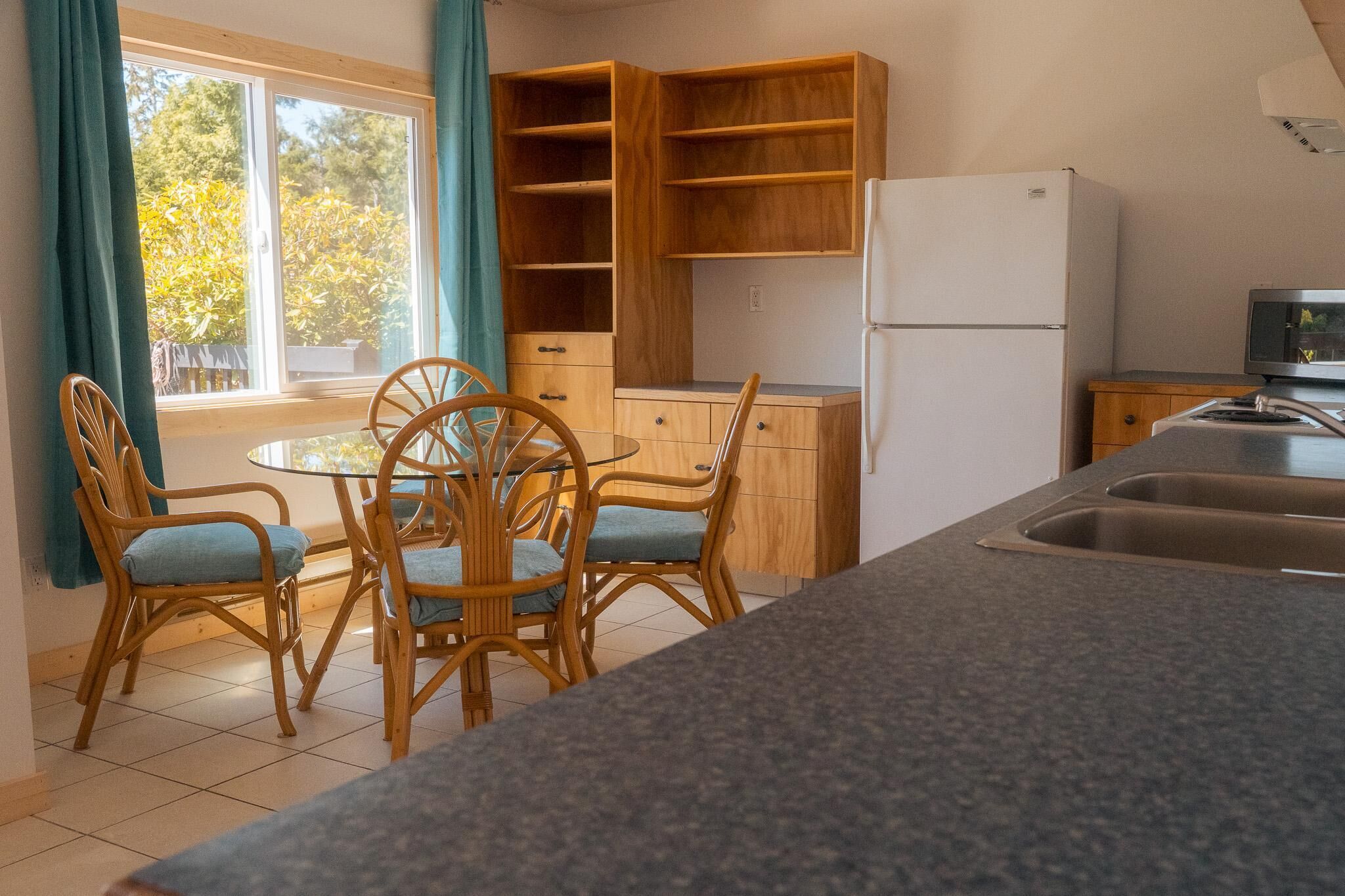 Una cocina con una mesa de comedor, sillas, un refrigerador y armarios de madera.