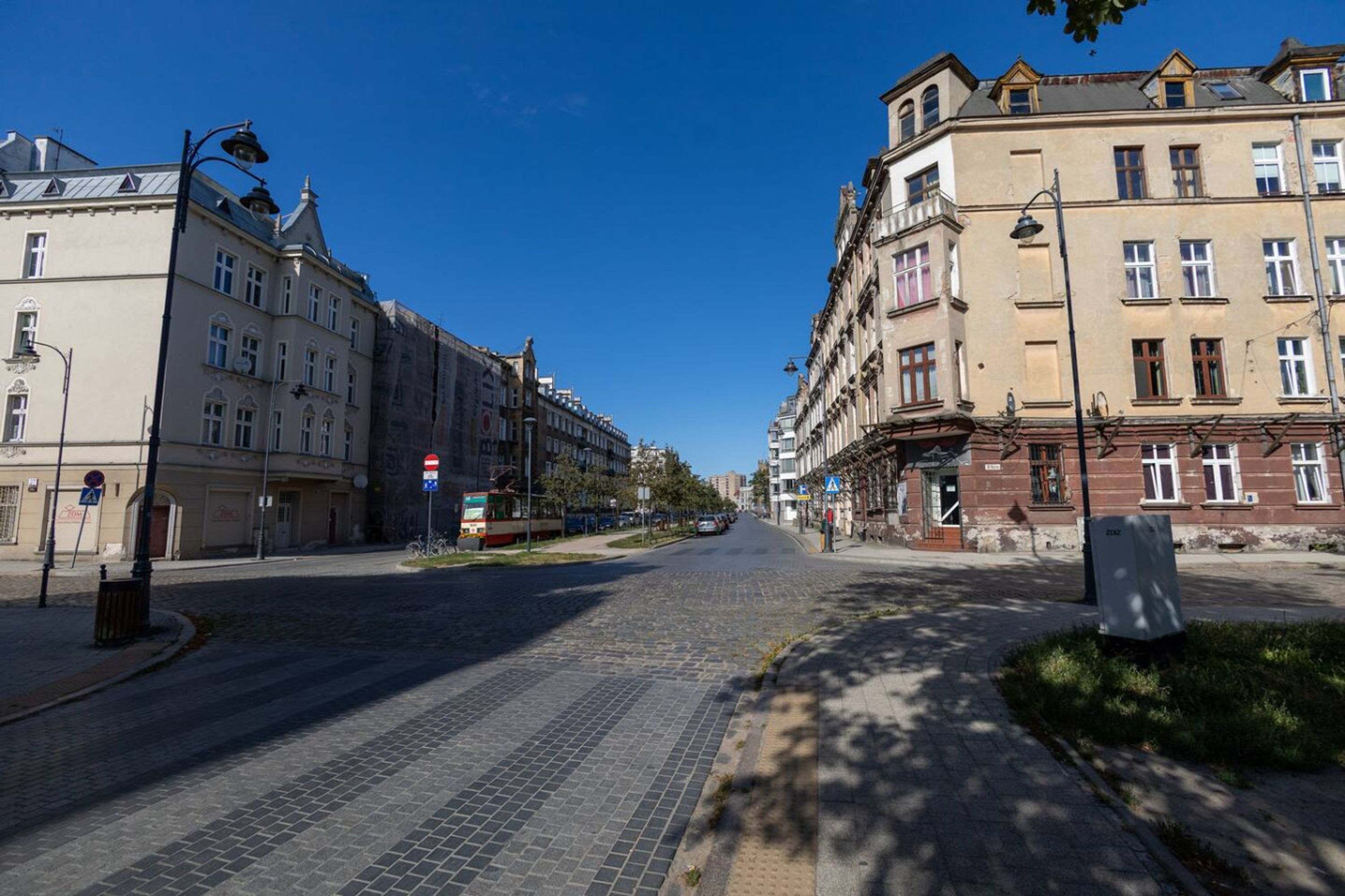 A street with historic buildings, cobblestone pavement, and a clear blue sky.