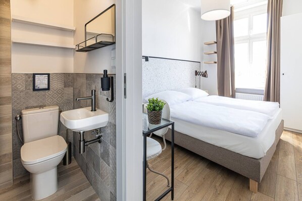 A modern bedroom with a bed, bedside table, and a small potted plant.