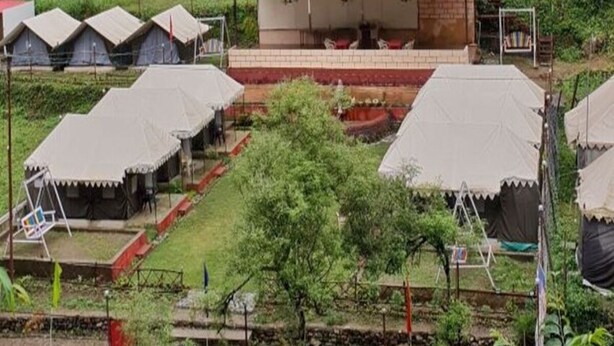 A rural accommodation with multiple tents and a central building with a red roof. - Eden RiverSide Camp (Lansdowne)