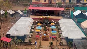 A campsite with tents, a dining area, and a building with a red roof. - Eden RiverSide Camp (Lansdowne)