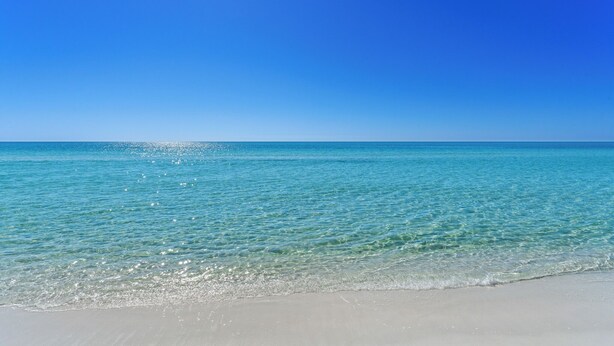 A beach with clear turquoise water and a bright blue sky.
