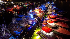 A marina at night with boats docked and illuminated by colorful lights.