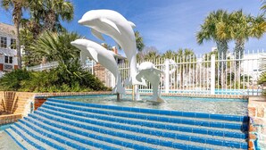 A pool with blue steps and a white dolphin sculpture.