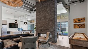 Un interior moderno con un pilar de piedra, sofá de cuero y una mesa de billar.