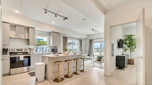 Una cocina moderna con una isla central, electrodomésticos de acero inoxidable y taburetes de bar.