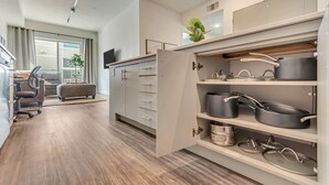 Eine moderne Küche mit Einbaugeräten, eine Essecke mit Sofa und Stuhl sowie ein großes Fenster mit Vorhängen.