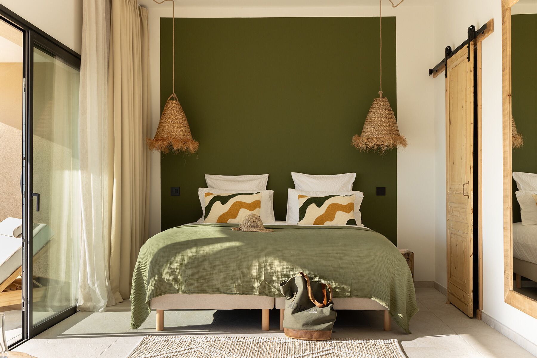 Un dormitorio con una cama, dos lámparas colgantes, una ventana y una puerta corredera.