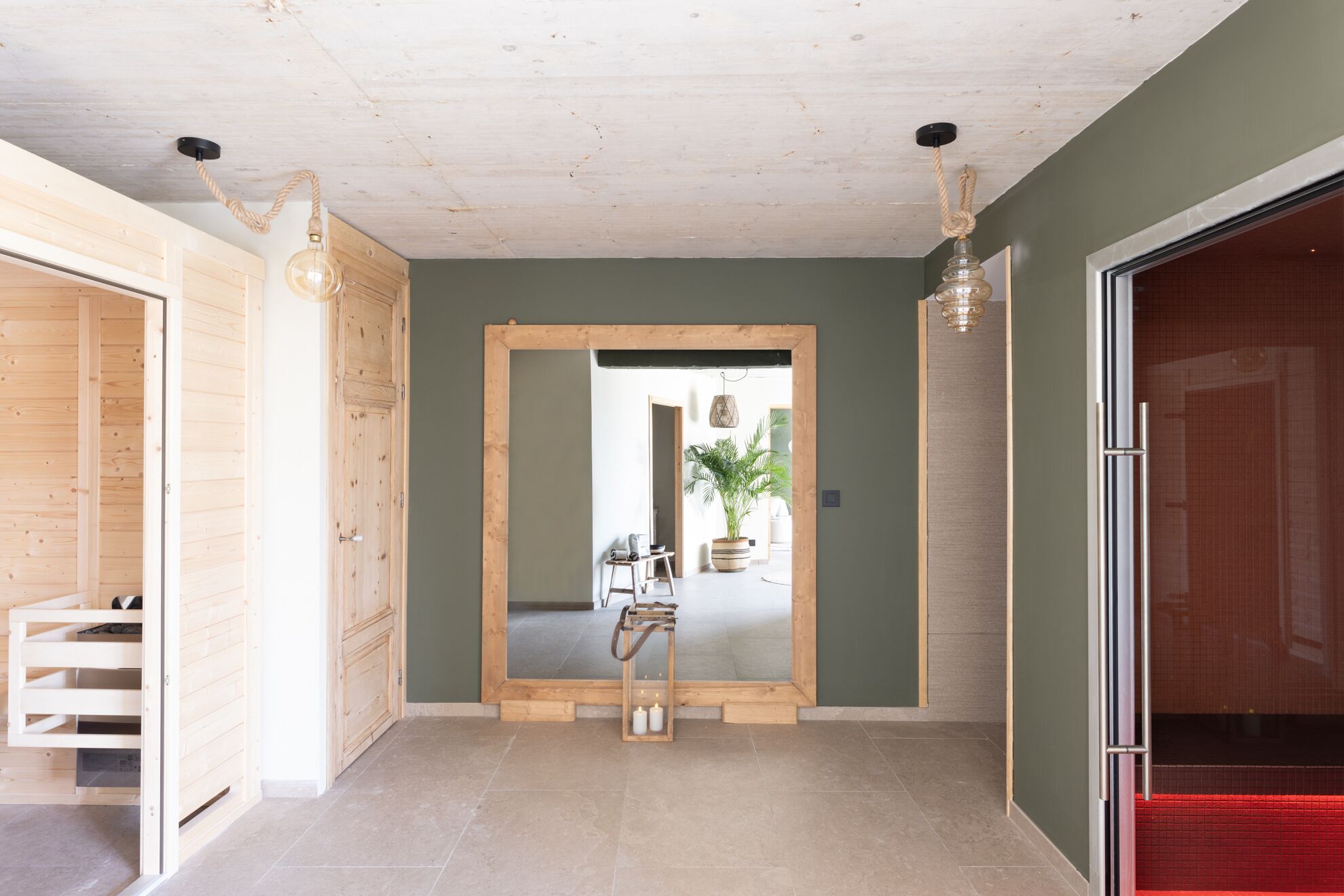 Un couloir avec une porte en bois, un miroir et une plante en pot.