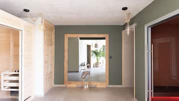 Un couloir avec une porte en bois, un miroir et une plante en pot.