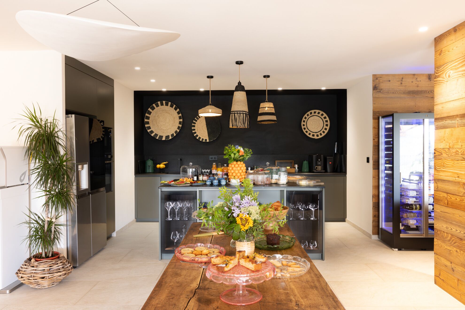 A modern kitchen with a central island, pendant lighting, and a wooden accent wall.