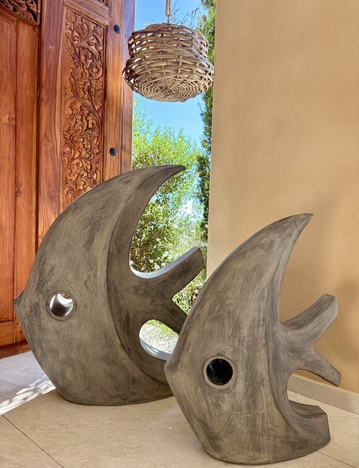 Two large, abstract fish sculptures with cutouts, placed on a tiled floor.